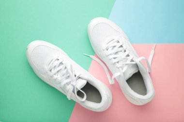 Renkli arka planda beyaz spor ayakkabılar. Üst görünüm