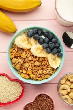 Pembe arka planda sağlıklı kahvaltı. Taze böğürtlenli granola. Üst görünüm