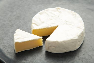 Koyu arkaplanda dilimlenmiş camembert peyniri. Üst görünüm