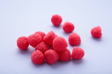 Böğürtlen şeklinde kırmızı çiğneme şekeri. Mor arkaplanda ahududu şeklinde tatlılar.