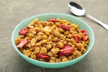 Gri arka planda bir kasede çilekli granola. Üst görünüm