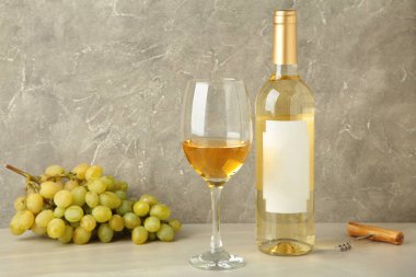 Gri arka planda üzümlü beyaz şarap şişesi ve cam. Üst görünüm