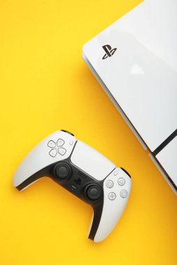 Mykolaiv, UKRAINE - Temmuz 2024: Beyaz konsol PlayStation 5 ve sarı arkaplanda oyun alanı.