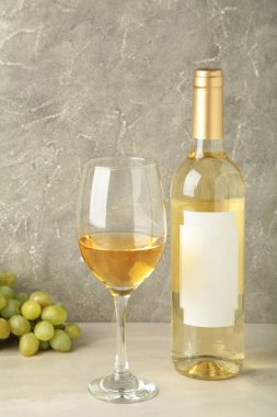 Hafif arka planda üzümlü beyaz şarap şişesi ve cam. Üst görünüm