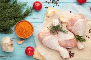 Mavi ahşap arka planda, tahtada baharatlı çiğ tavuk budu..