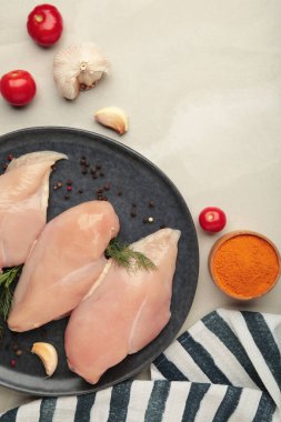 Tabakta çiğ tavuk filetosu, domates, baharat ve siyah arka planda dereotu..