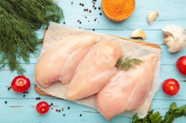 Kesme tahtasında çiğ tavuk filetosu domates, baharat ve ahşap kaplama dereotlu..