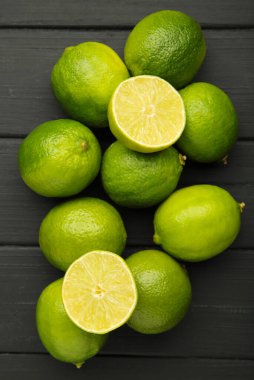 Siyah ahşap arka planda ikiye bölünmüş yeşil kireç. Dikey fotoğraf