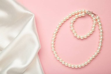 Pembe arka planda beyaz ipekli inci kolye..