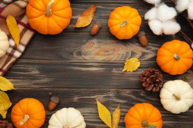 Sonbahar kompozisyonu. Kahverengi ahşap arka planda sonbahar yaprakları olan taze portakal ve beyaz balkabağı..