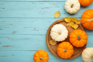 Taze portakal ve beyaz balkabağı ahşap tabakta Sonbahar yaprakları mavi arka planda.