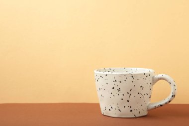 Bej arka planda siyah parıltılı seramik beyaz bardak. en üstteki görünüm