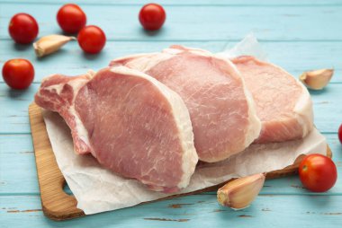 Mavi ahşap arka planda dilimlenmiş çiğ domuz eti. Üst görünüm