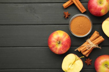 Kırmızı elma, tarçın çubukları ve siyah ahşap arka planda tarçın. Metin için boşluk