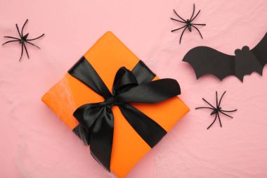 Örümcekli yapay örümcek ağı dekorasyonu ve pembe arka planda hediye..