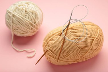 Pembe arka planda hafif örgü iplikleri ve iğneler. Üst görünüm