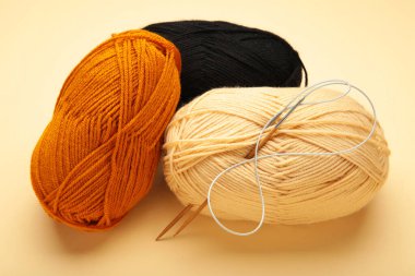 Farklı iplikler, bej arka planda örgü iğneleri. Üst görünüm