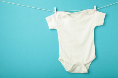 Mavi arka planda beyaz bebek tulumu. Üst görünüm