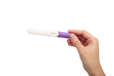Genç yetişkin kadın ellerinde hamilelik testi, beyaz arka planda iki şerit var..
