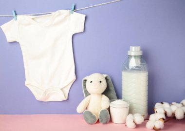 Çamaşır deterjanı ürünleri beyaz bebek bezi ve mor arka planda pamuk çiçeği..