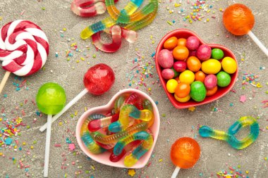 Gri arkaplanda farklı tipte şekerler, kopyalama alanı. Renkli doğum günü partisi geçmişi.