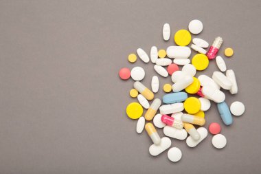 Gri arka planda çeşitli renkli haplar. Üst görünüm