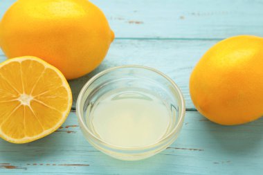 Bir bardak sıkılmış limon suyu ve mavi ahşap arka planda limon. Üst görünüm