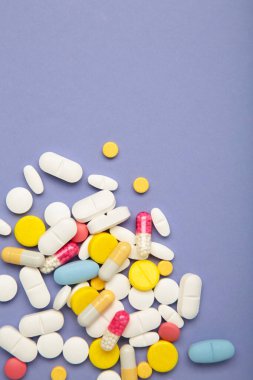 Mor arka planda çeşitli renkli haplar. Üst Manzara. Dikey fotoğraf