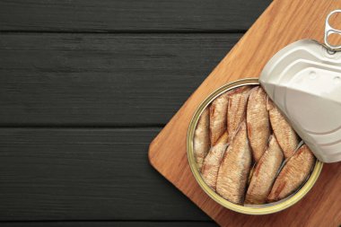 Siyah ahşap arka planda kavanozda tütsülenmiş balık..