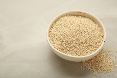 Beyaz kasede, arka planda çiğ susam tohumları. Üst görünüm.