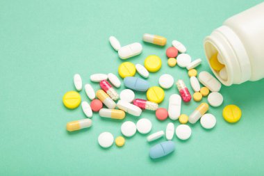 Çeşitli ilaç hapları, haplar, kapsüller ve nane arkaplanlı bir şişe. Üst görünüm