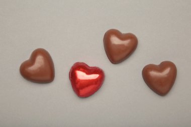 Kırmızılı çikolatalar, gri arkaplandaki kalp gibidir. Sevgililer Günü konsepti. Üst görünüm