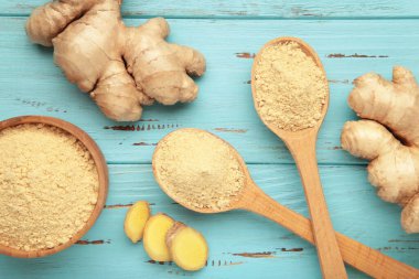 Kasede zencefil tozu, mavi ahşap arka planda taze zencefil kökü..