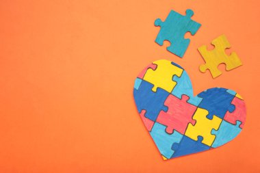 Turuncu arka planda renkli yapboz kalbi. Dünya Otizm Farkındalık Günü 'nün sembolü olarak çok renkli kalp