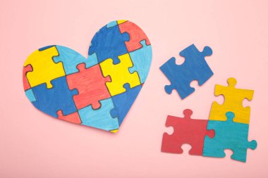 Pembe arka planda renkli yapboz kalbi. Dünya Otizm Farkındalık Günü 'nün sembolü olarak çok renkli kalp