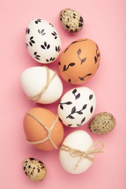 Paskalya yumurtalı kompozisyon pembe arka planda. Dikey fotoğraf