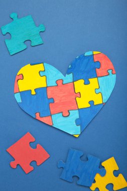 Mavi arka planda renkli yapboz kalbi. Dünya Otizm Farkındalık Günü 'nün sembolü olarak çok renkli kalp. Dikey fotoğraf