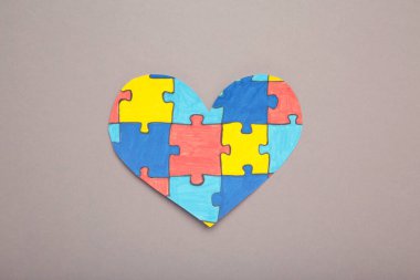 Gri arka planda renkli yapboz kalp. Dünya Otizm Farkındalık Günü 'nün sembolü olarak çok renkli kalp