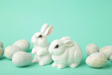 Renkli paskalya yumurtaları ve arkaplanda seramik tavşan heykelcikleri. Üst görünüm