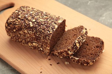 Arka planda kesim tahtasında karışık tohumlu buğday ekmeği. Üst görünüm