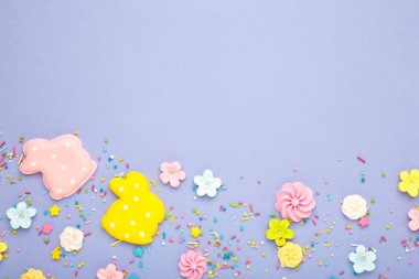 Tavşanda lezzetli Paskalya kurabiyeleri ve mor arka planda şekerler. Üst görünüm