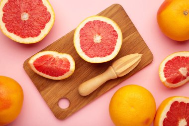 Taze organik greyfurt ve pembe arka planda ahşap meyve sıkacağı. Metin için boşluk