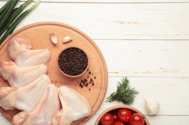 Çiğ tavuk kanadı, ahşap tahta üzerinde yemek pişirmek için gerekli malzemeler.