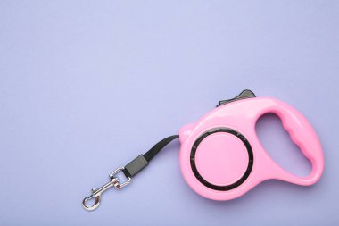 Mor arka plandaki evcil hayvanlar için pembe plastik dayanıklı ve ergonomik tasma ruleti. Üst görünüm