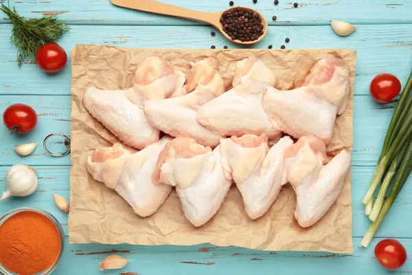 Çiğ tavuk kanadı ve ahşap tahta üzerinde yemek pişirmek için malzemeler.