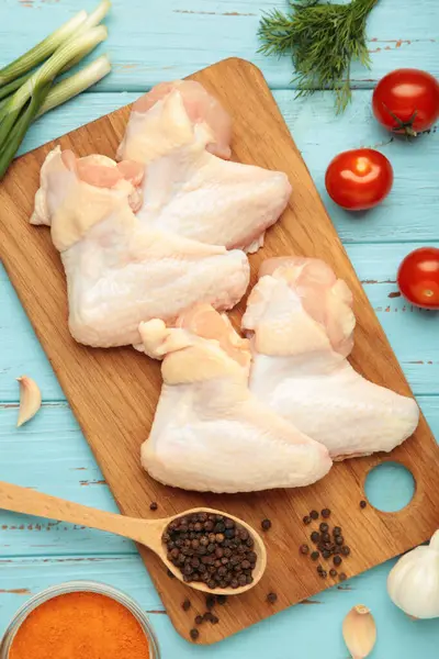 Çiğ tavuk kanadı ve ahşap tahta üzerinde yemek pişirmek için malzemeler.