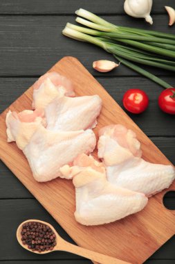 Çiğ tavuk kanatları, ahşap kesim tahtasında pişirmek için malzemeler, ahşap arka plan, üst manzara.