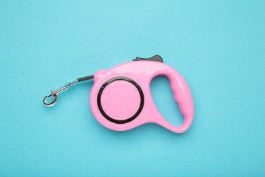 Mavi arka plandaki evcil hayvanlar için pembe plastik dayanıklı ve ergonomik tasma ruleti. Üst görünüm