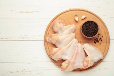 Çiğ tavuk kanadı, ahşap tahta üzerinde yemek pişirmek için gerekli malzemeler.