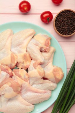 Çiğ tavuk kanadı. Nane tabağında pişirecek malzemeler var. Pembe ahşap arka planda.